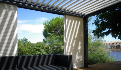 Terrasse ombragée avec vue sur jardin et rivière.
