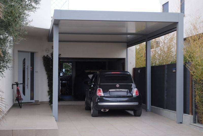 Voiture noire garée sous un carport moderne.