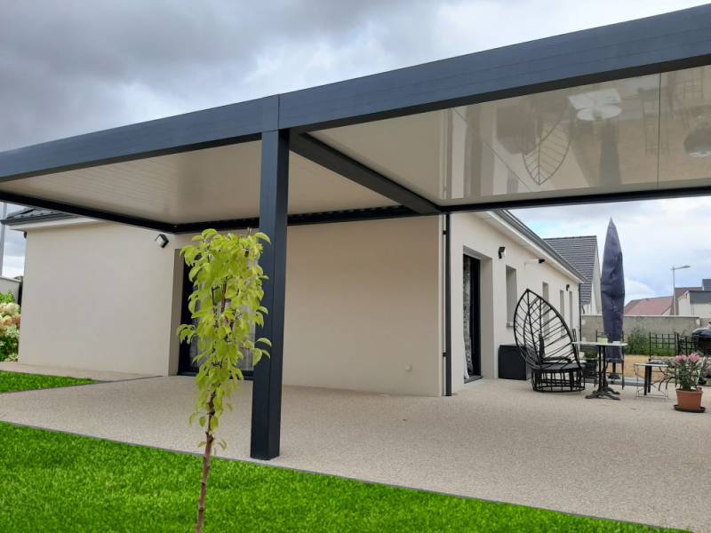 Maison moderne avec terrasse couverte et jardin verdoyant.
