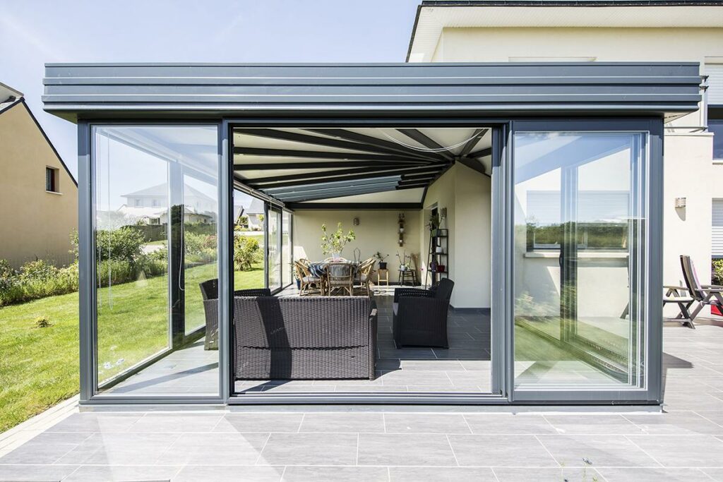 Grande véranda moderne avec chaises et table.