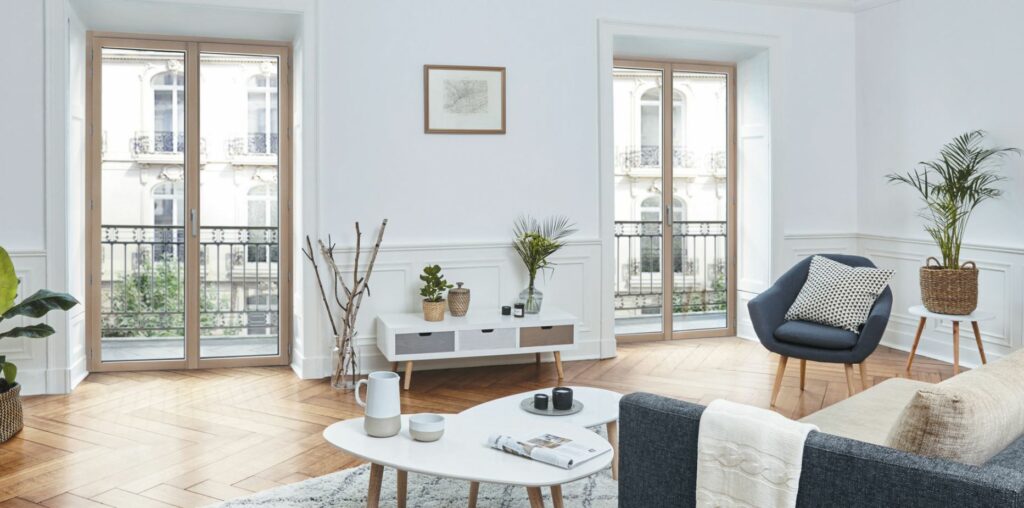 Salon lumineux avec parquet et grandes fenêtres.